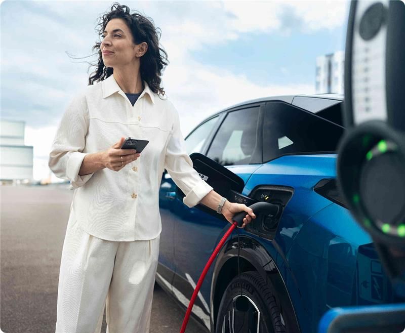 chica con pelo rizado cargando un coche electrico