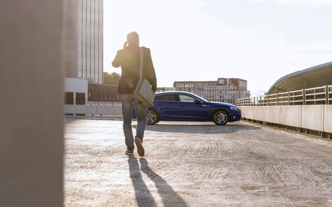 Hombre yendo hacia su coche aparcado en una plaza de parking al aire libre
