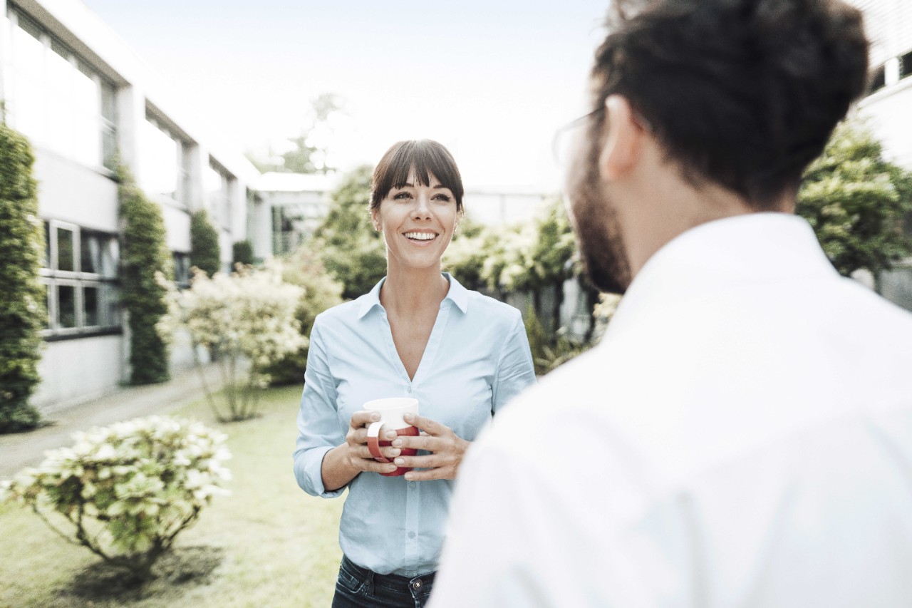 Mujer hablando felizmente con su compañero en el patio de las oficinas 