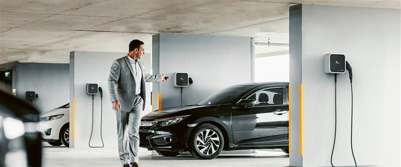 coche electrico cargando mientras un chico lo cierra