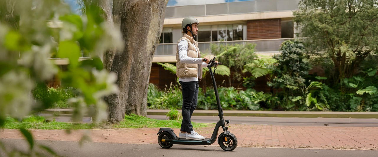 Hombre en patinete con casco y por zona urbana