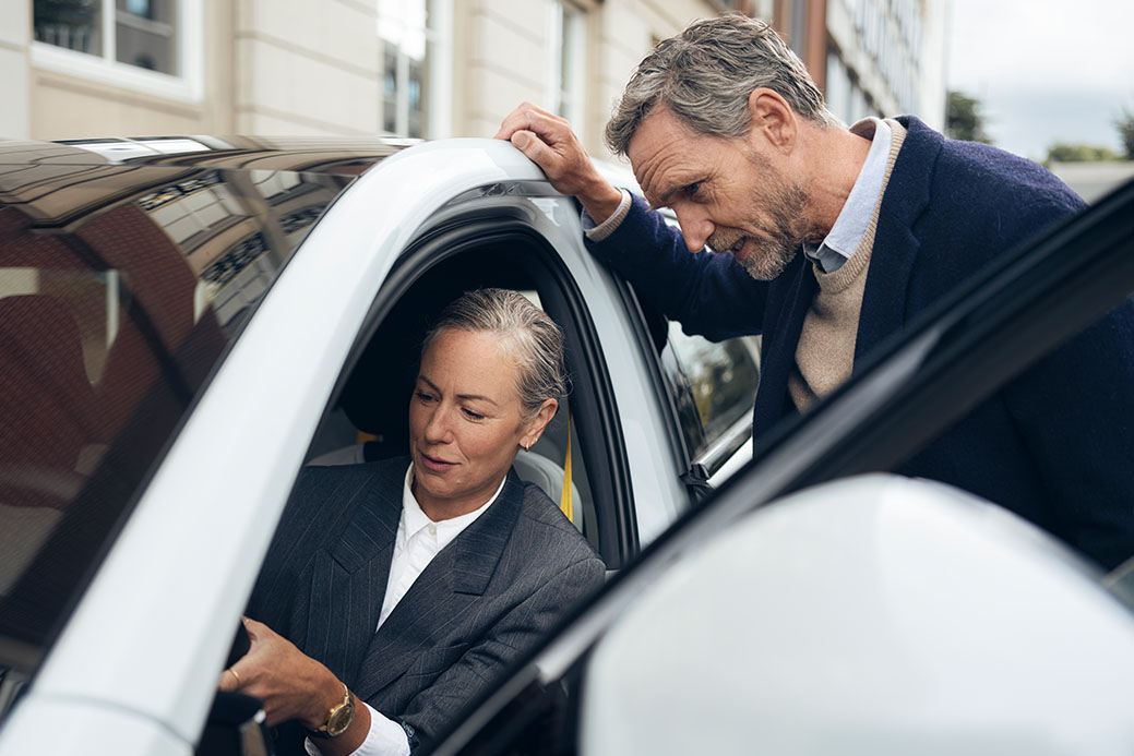 hombre y mujer hablando en la puerta de un coche