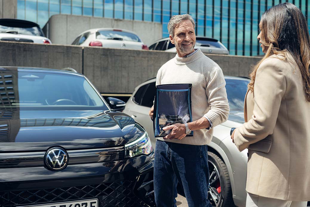 hombre mostrando un coche a una mujer en un parking