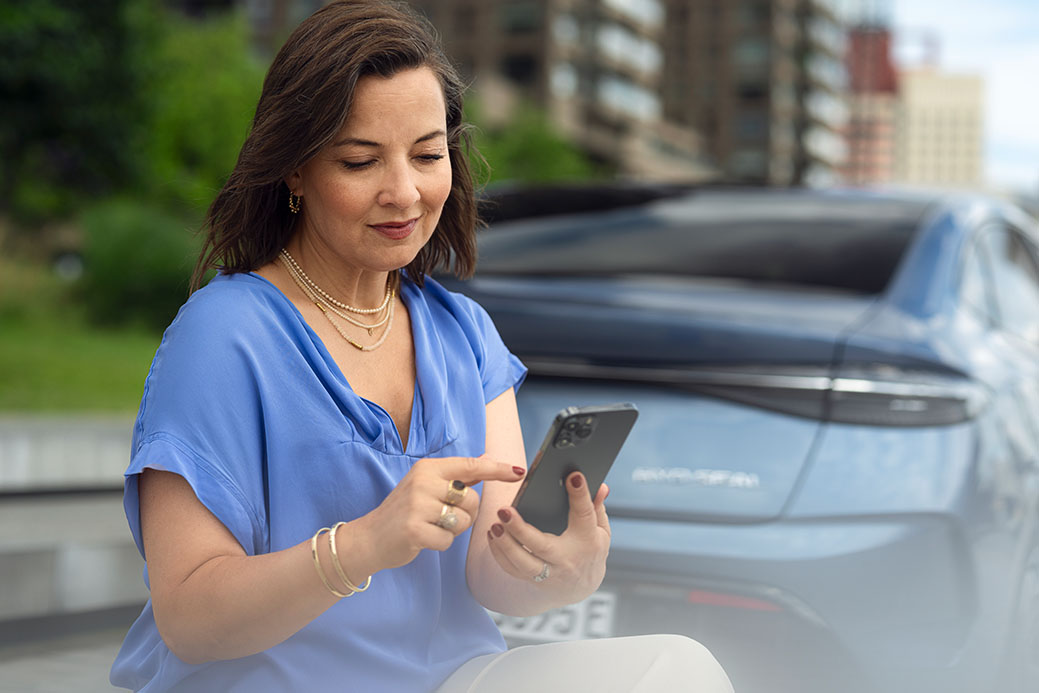 mujer con blusa azul escribiendo por el movil