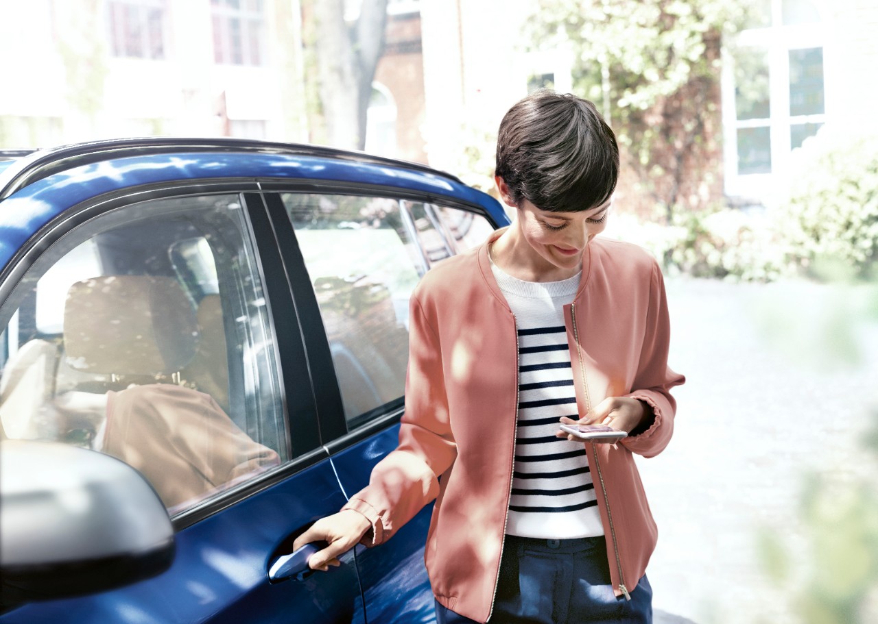 mujer mirando el telefono saliendo del coche