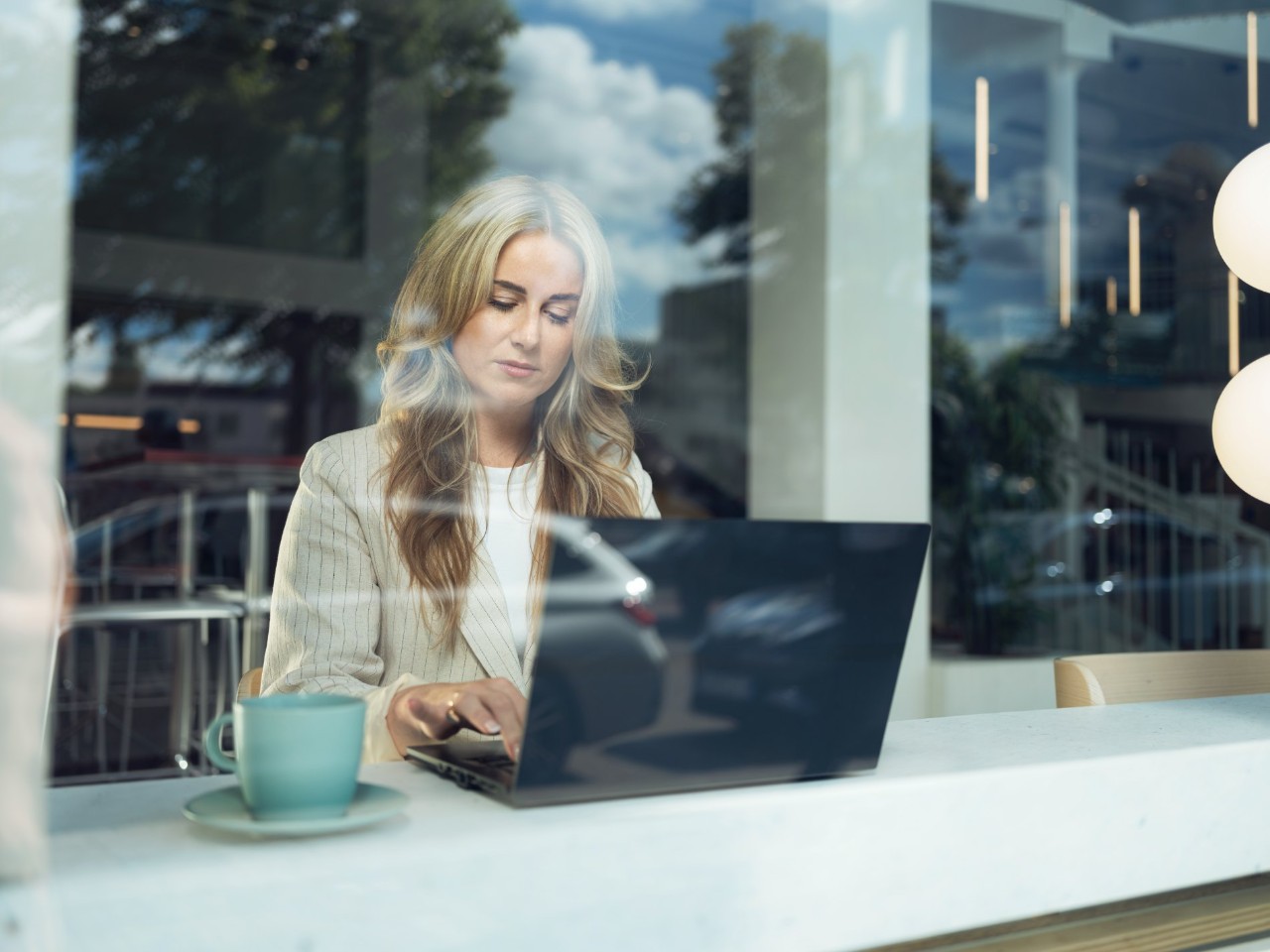 Chica rubia con un ordenador tras un cristal repasando los valores corporativos de Alphabet