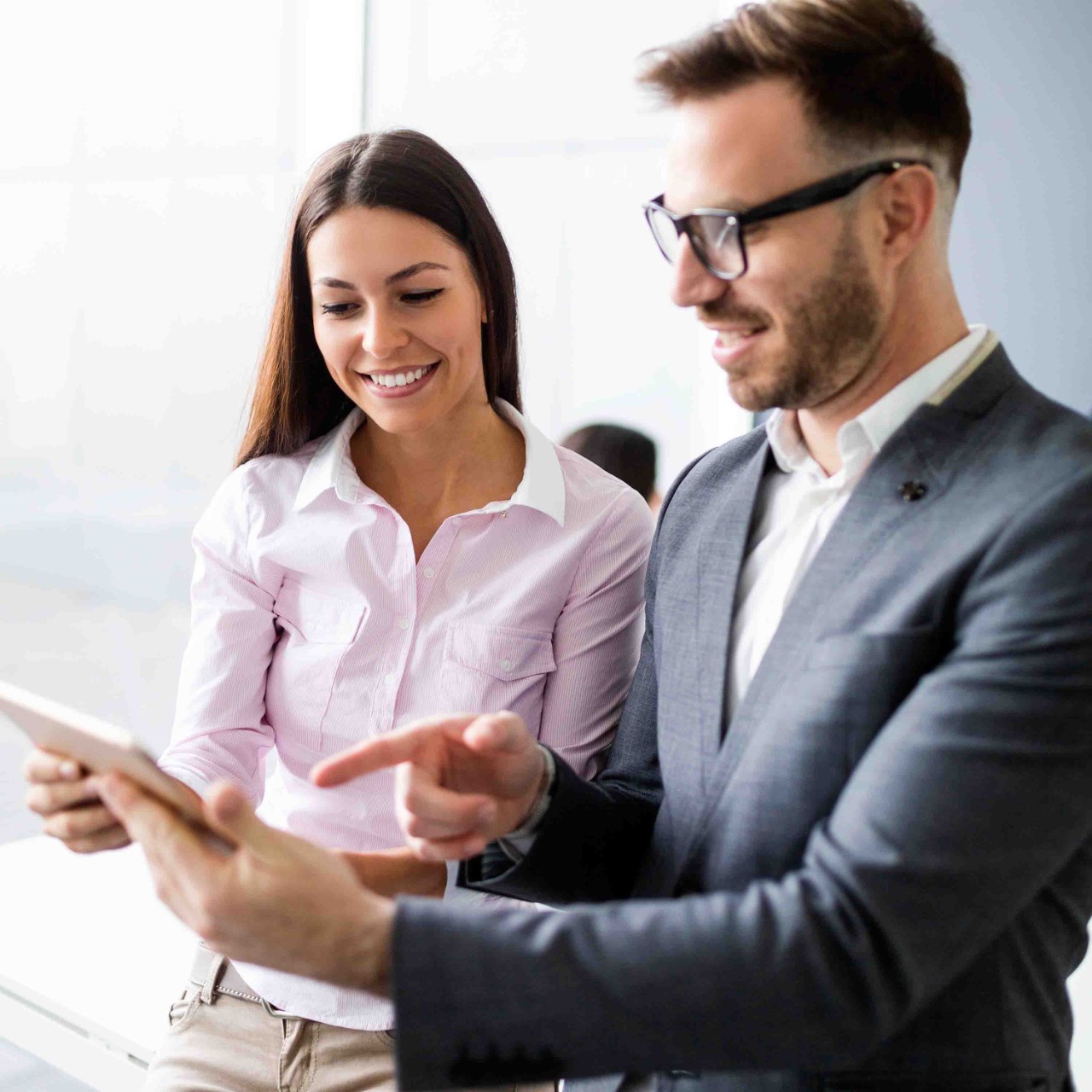 chica con camisa rosa y chico con americana mirando una tablet