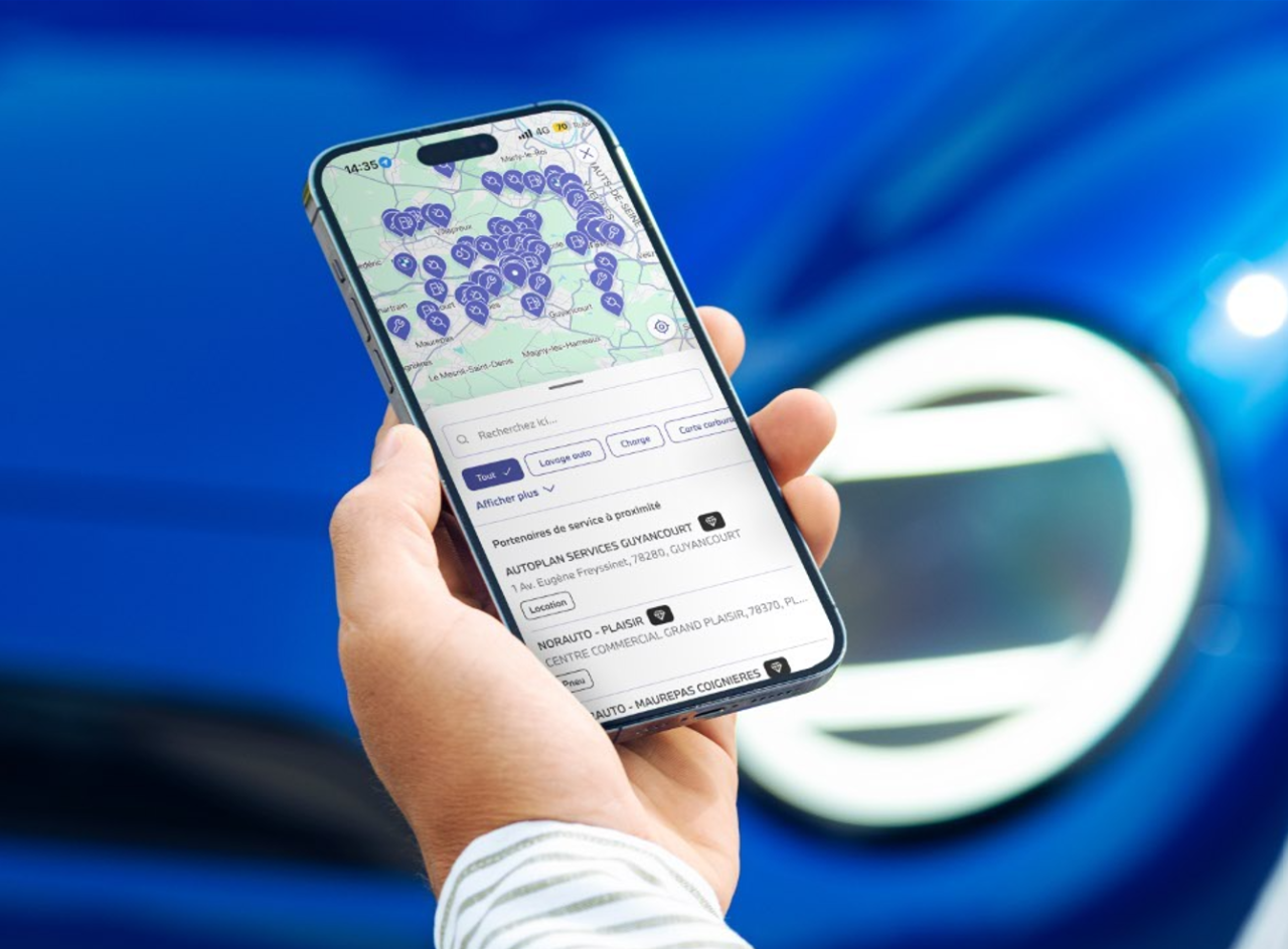 Woman outside a car with the door open and looking at a smartphone screen.