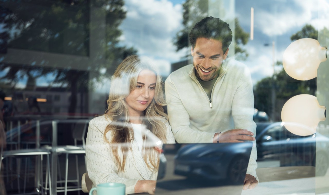 Homme et femme derrière une vitre travaillant derrière un écran