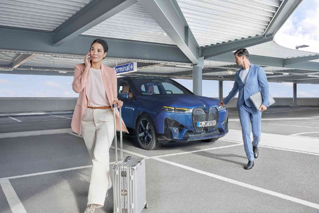 Een man en een vrouwen lopen weg bij een blauwe BMW.