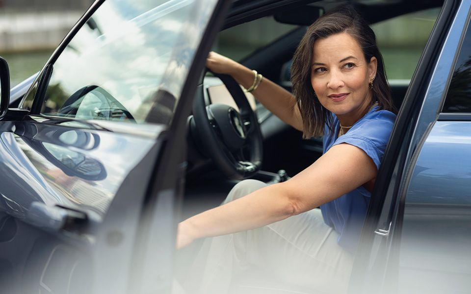 Vrouw stapt uit haar blauwe auto.