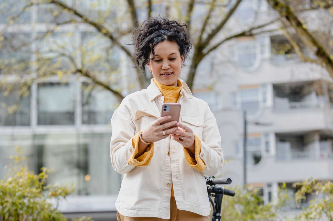 Vrouw met een witte jas kijkt met een glimlach op haar telefoon.
