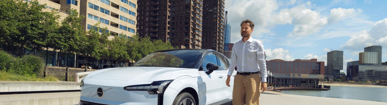 Man loopt naast zijn witte Volvo.