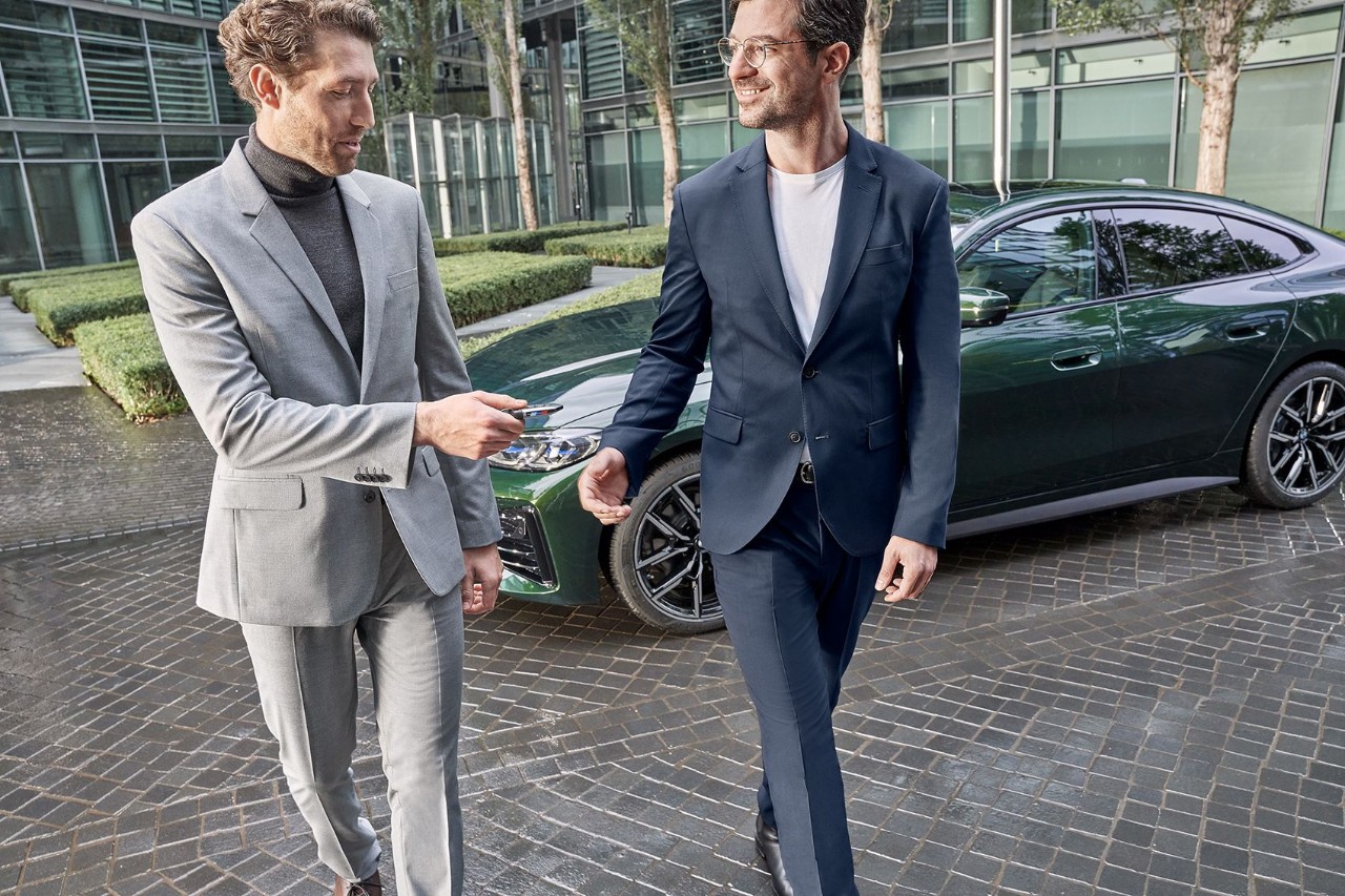 Twee mannen lopen voor een groene BMW.