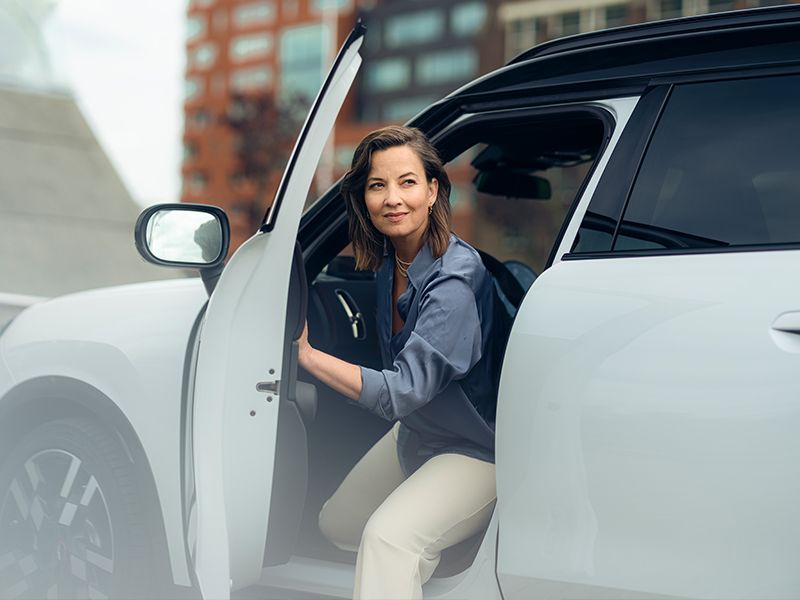 Vrouw stapt uit haar witte auto.