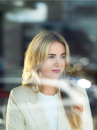 Vrouw kijkt met een glimlach uit het raam.
