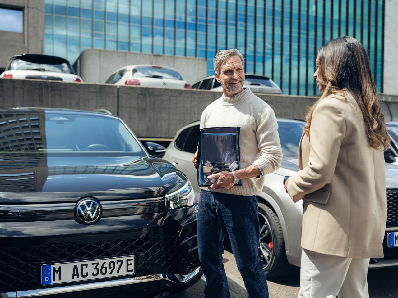 Twee personen staan voor een Volkswagen.