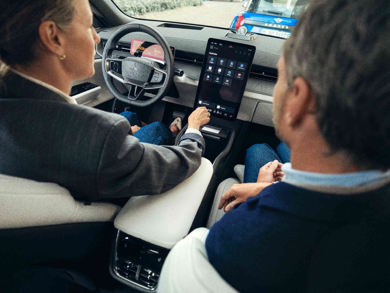 Twee personen in blazers zitten in de auto en kijken naar het centrale display perspectief van de hoofdsteun van de passagier.
