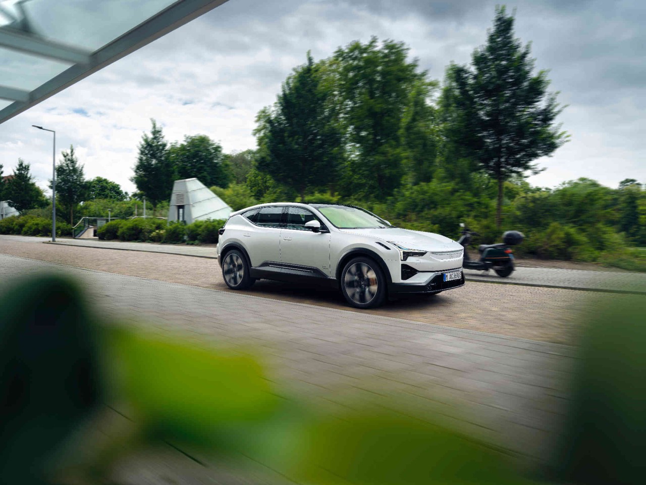 Witte auto rijdt op een geplaveide straat groene landschap op de achtergrond.