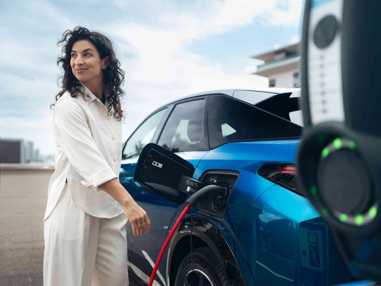 Vrouw laadt elektrische auto op aan laadstation groene lichten tonen actieve laadprocedure.