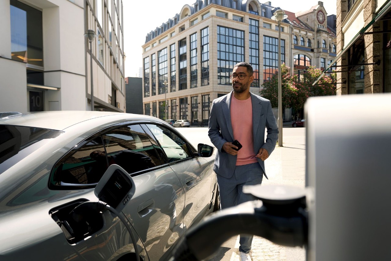 Man staat naast zijn auto bij het oplaadstation