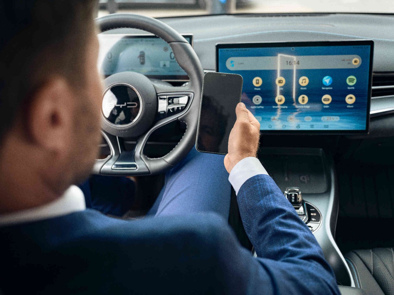 Man zit op de bestuurdersstoel in de auto en kijkt op zijn telefoon.