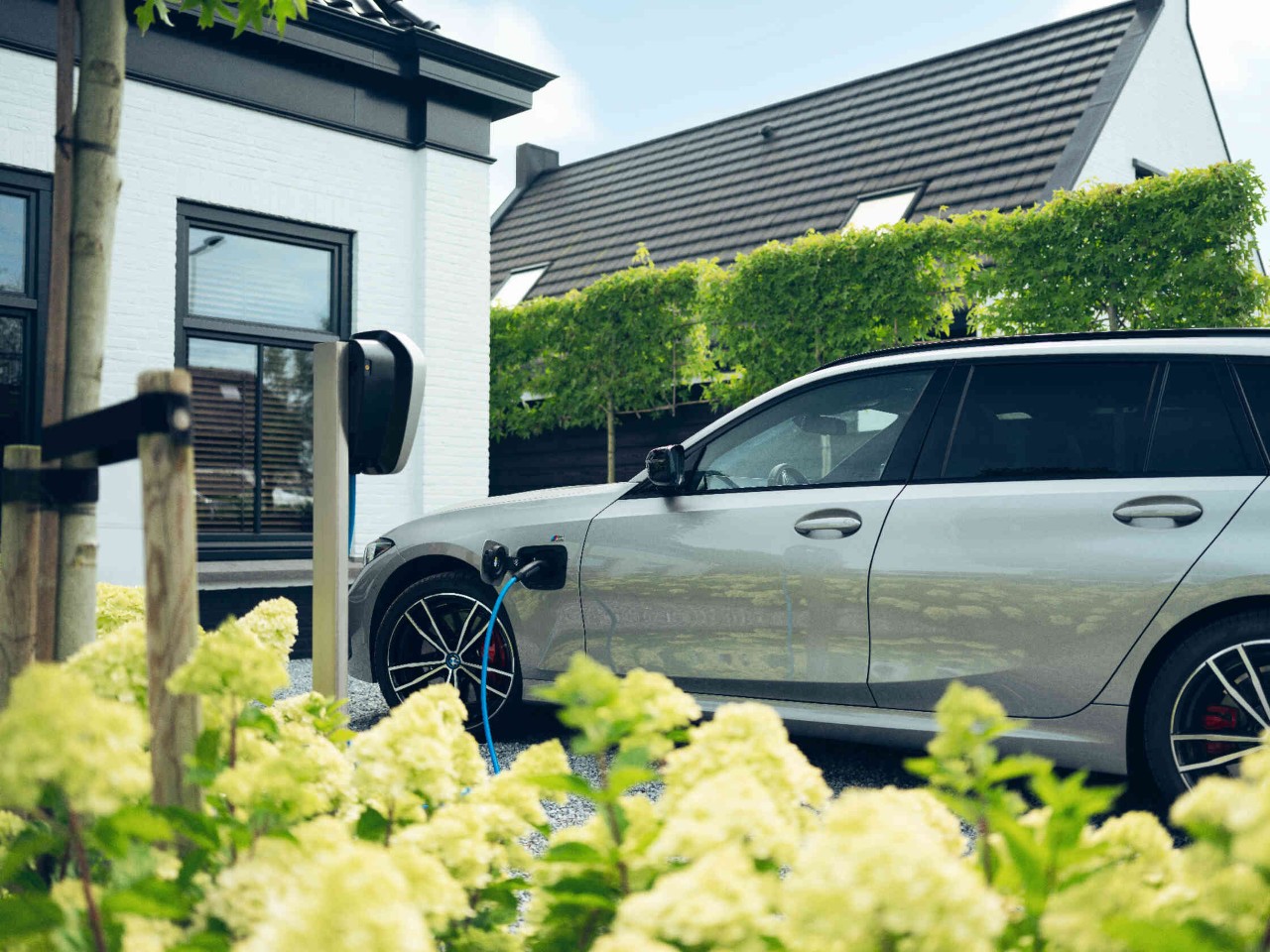 Grijze auto staat voor een huis en wordt opgeladen.