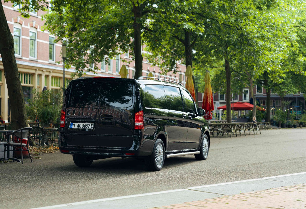 Een zwarte bestelwagen staat voor een lege horecagelegenheid.