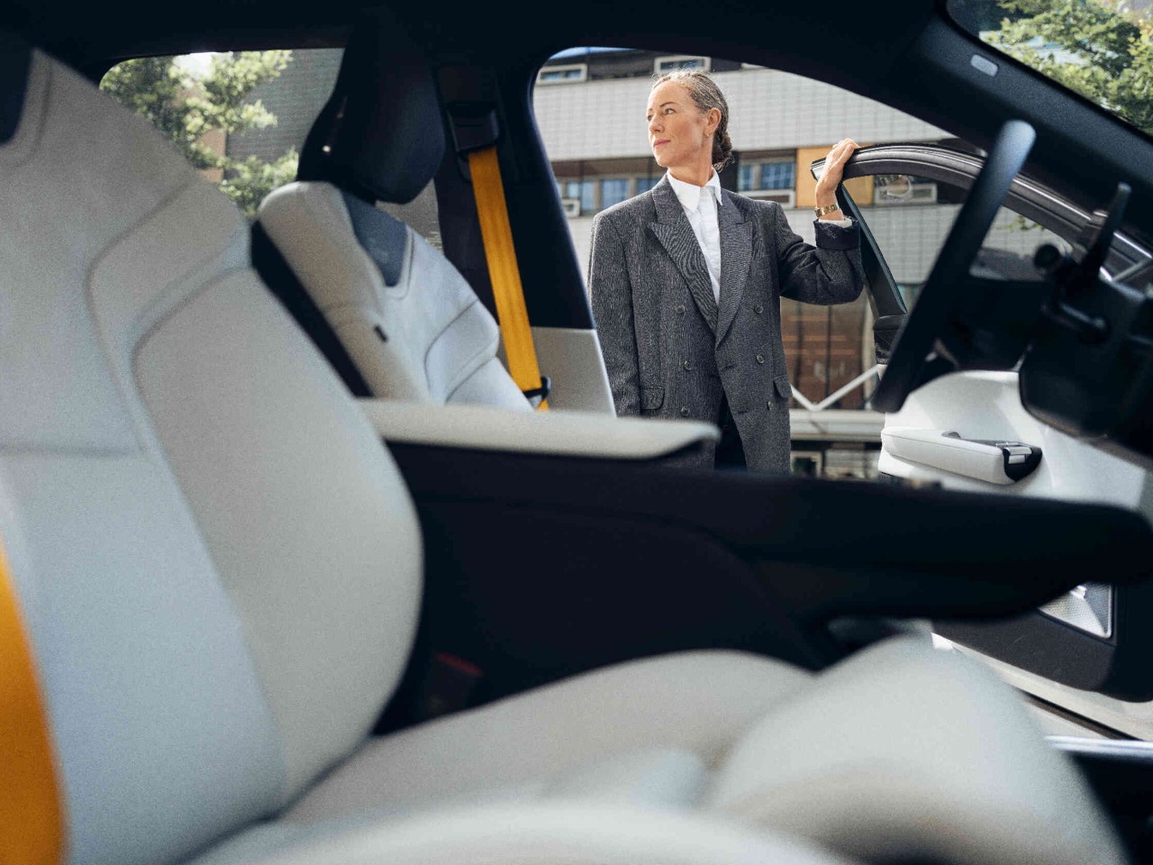 Vrouw staat in de bestuurdersdeur van een auto met elegante binnenafwerking perspectief vanuit de passagiersstoel.
