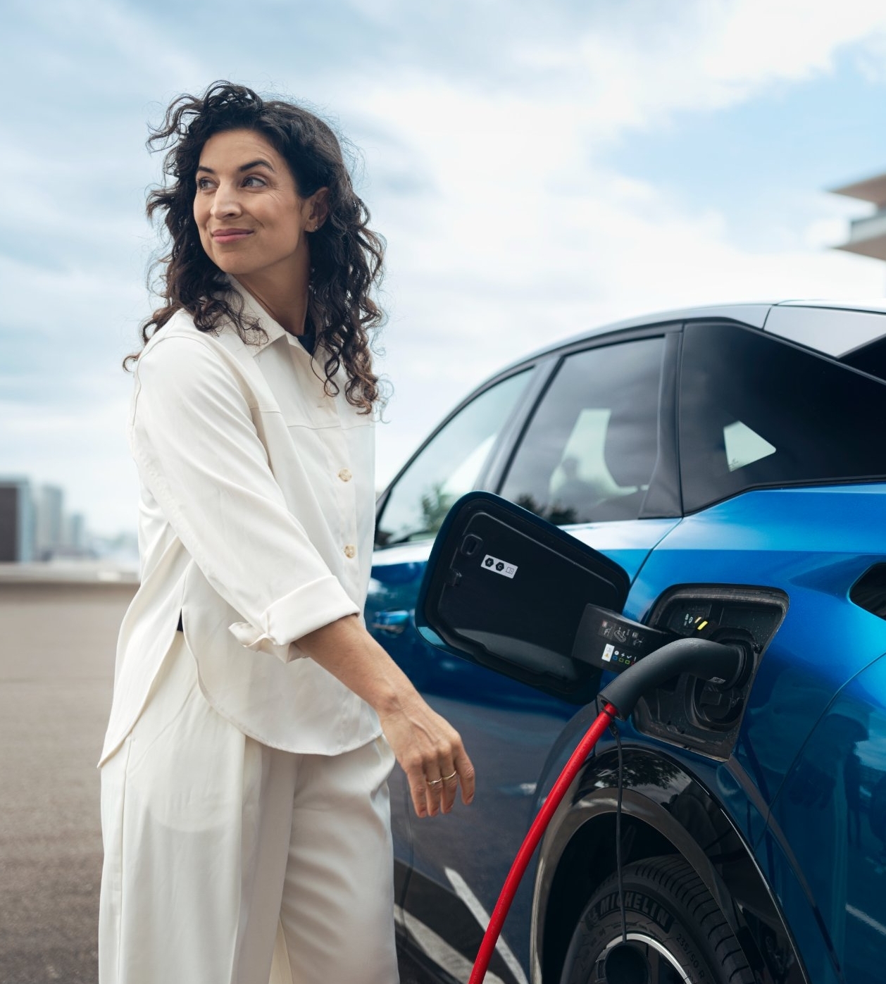Woman charges an electric car at a charging station.