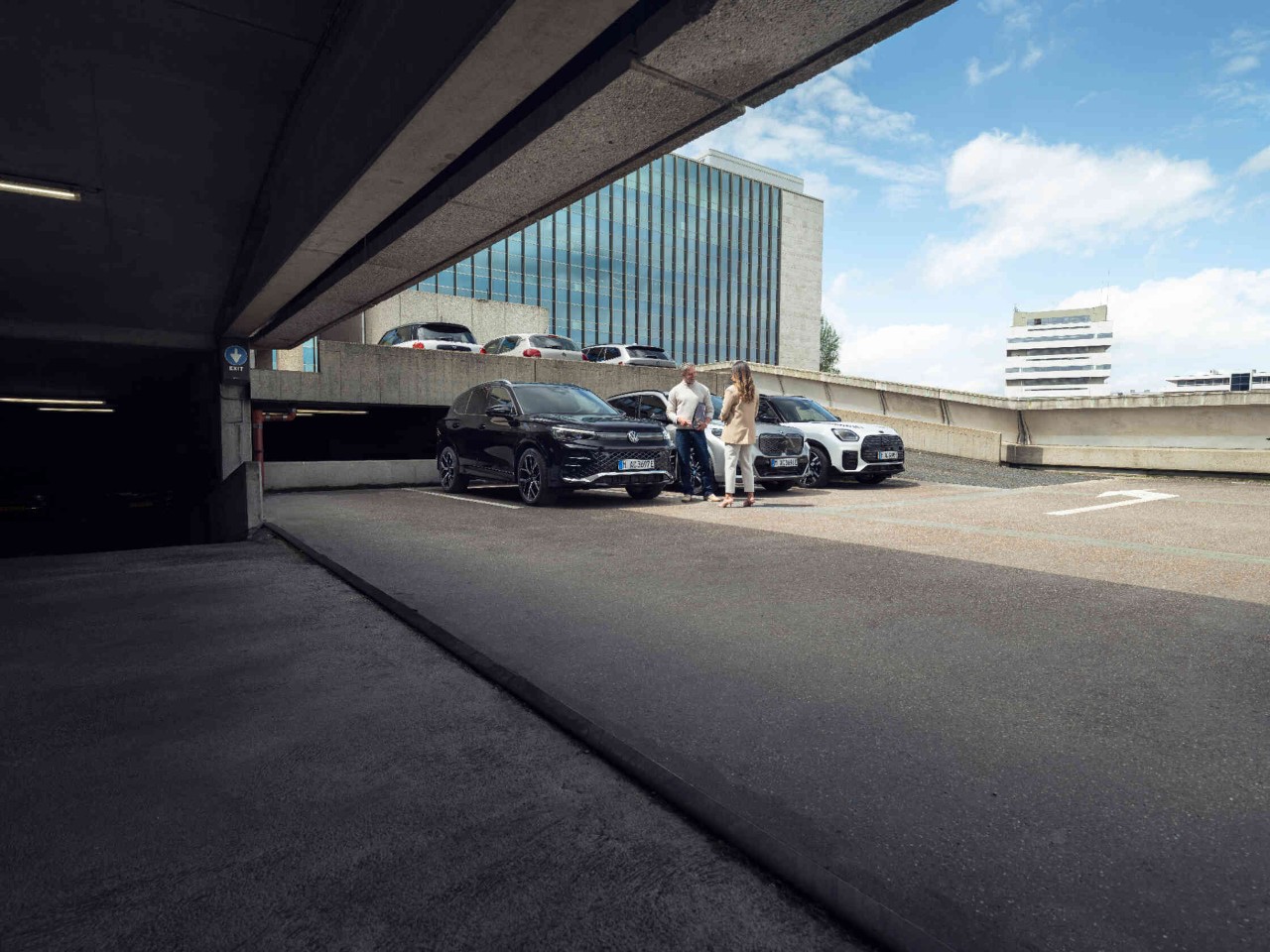 Twee personen naast auto's moderne gebouwen op de achtergrond.