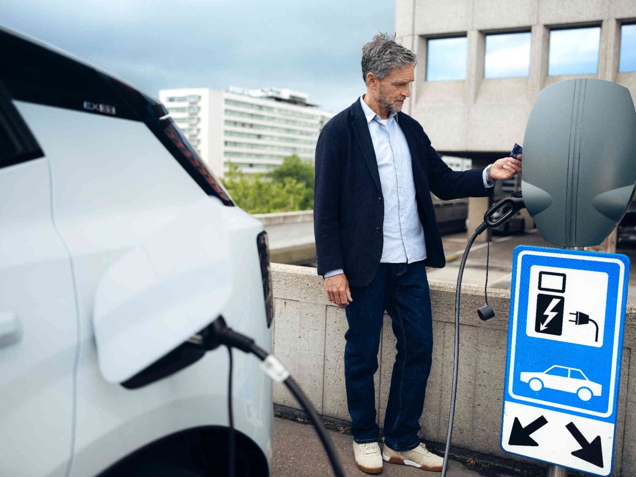 Een man staat naast een laadstation voor elektrische voertuigen houdt een kaart om het station te activeren.