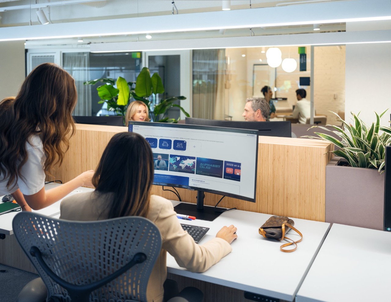 Twee vrouwen met donker haar achter een gebogen monitor.