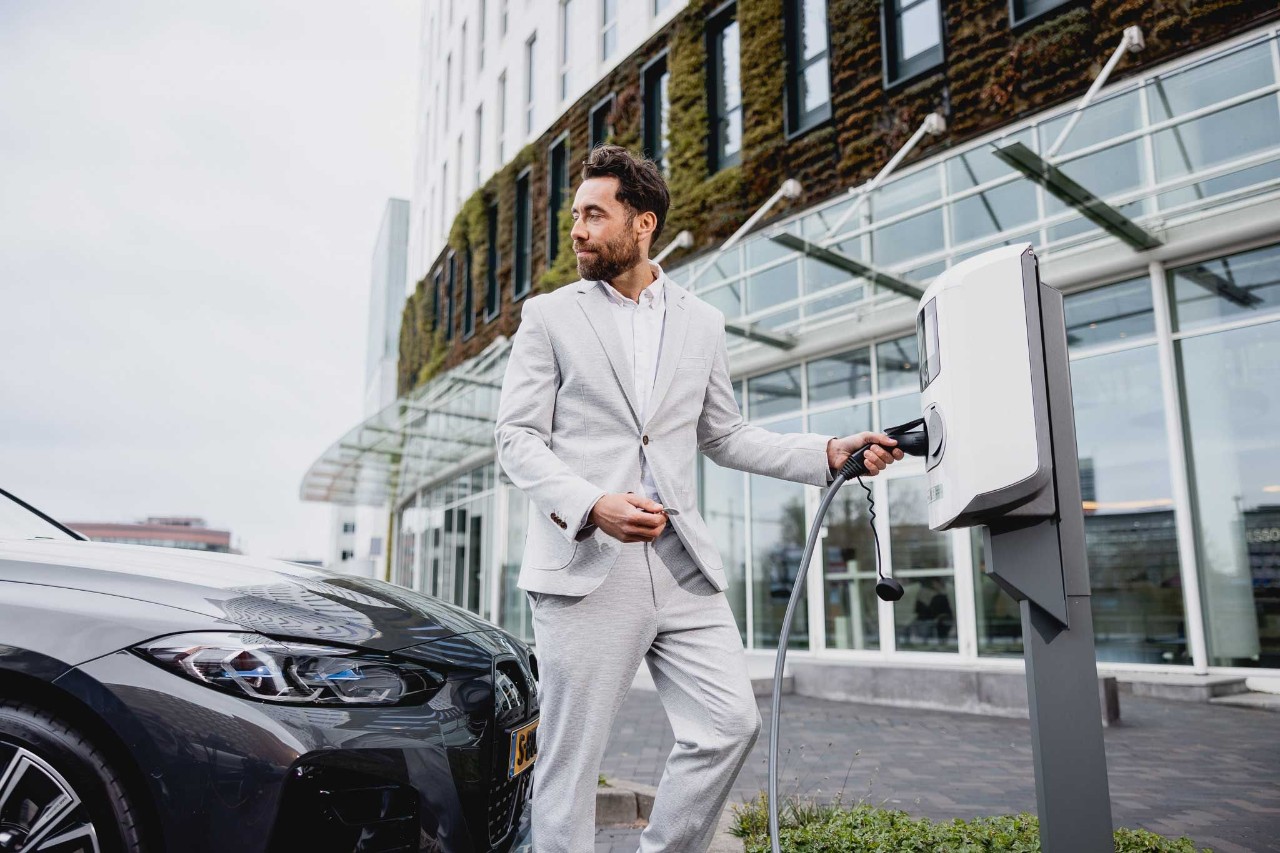 Man in pak gaat zijn BMW i4 aansluiten op de oplaadstekker