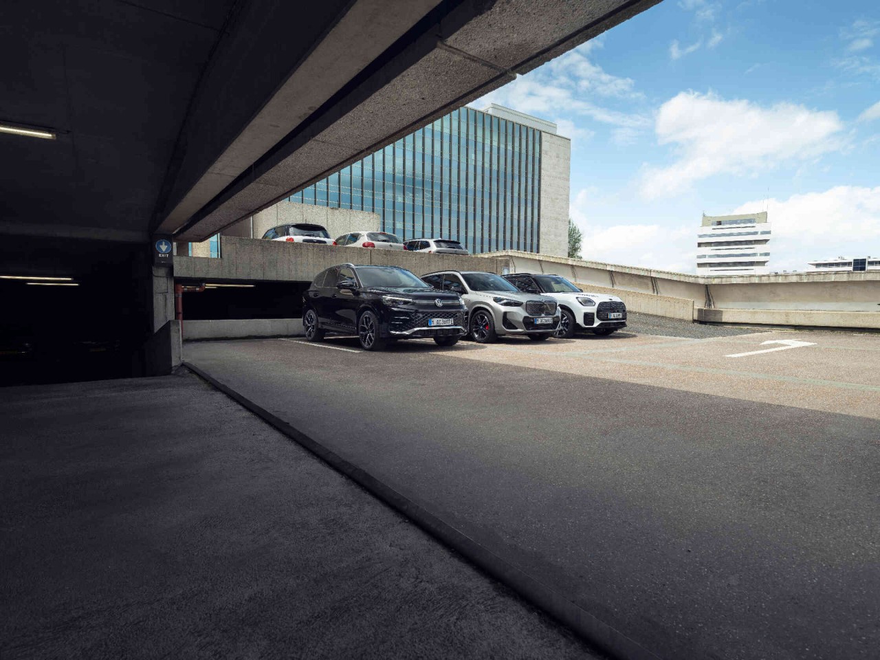 Drie auto's in stedelijke parkeergarage modern kantoorgebouw op de achtergrond.