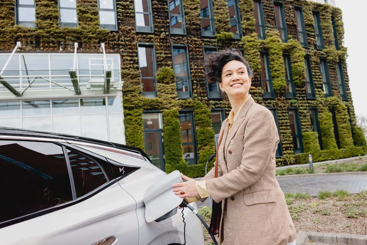 Een vrouw laadt een elektrische auto op bij een laadstation.