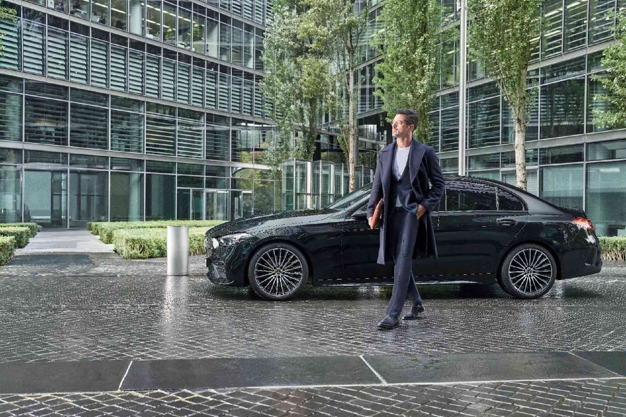 Man loopt voor een zwarte Mercedes CLA