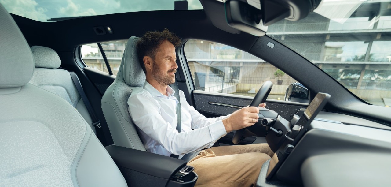 Een man zit alleen in een auto en rijdt met een geconcentreerde blik op de weg.