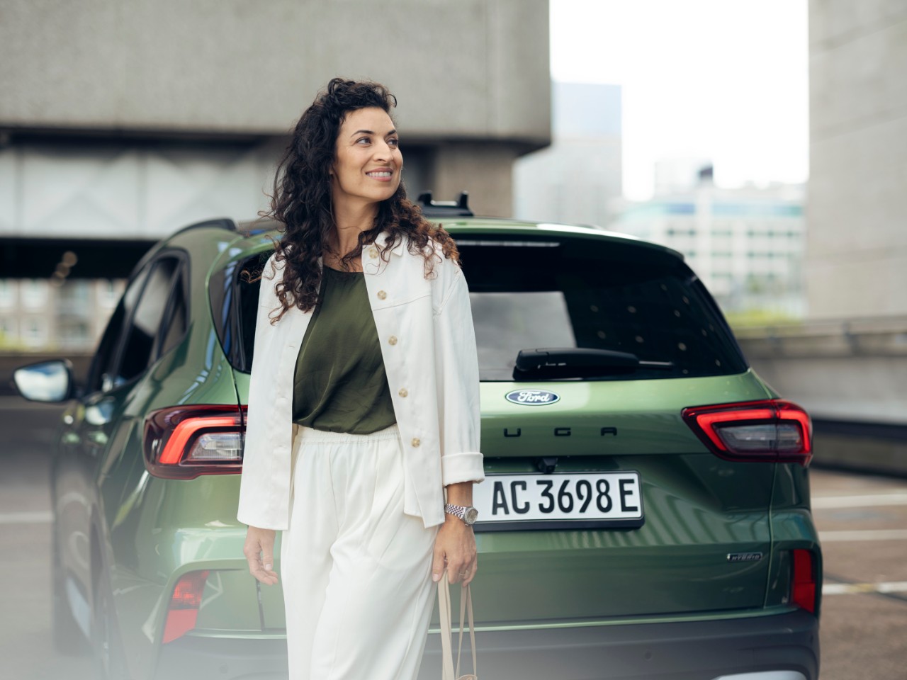 Mann sitzt auf Fahrersitz eines stehendes Autos schaut auf sein Handy Fahrertuer steht offen.